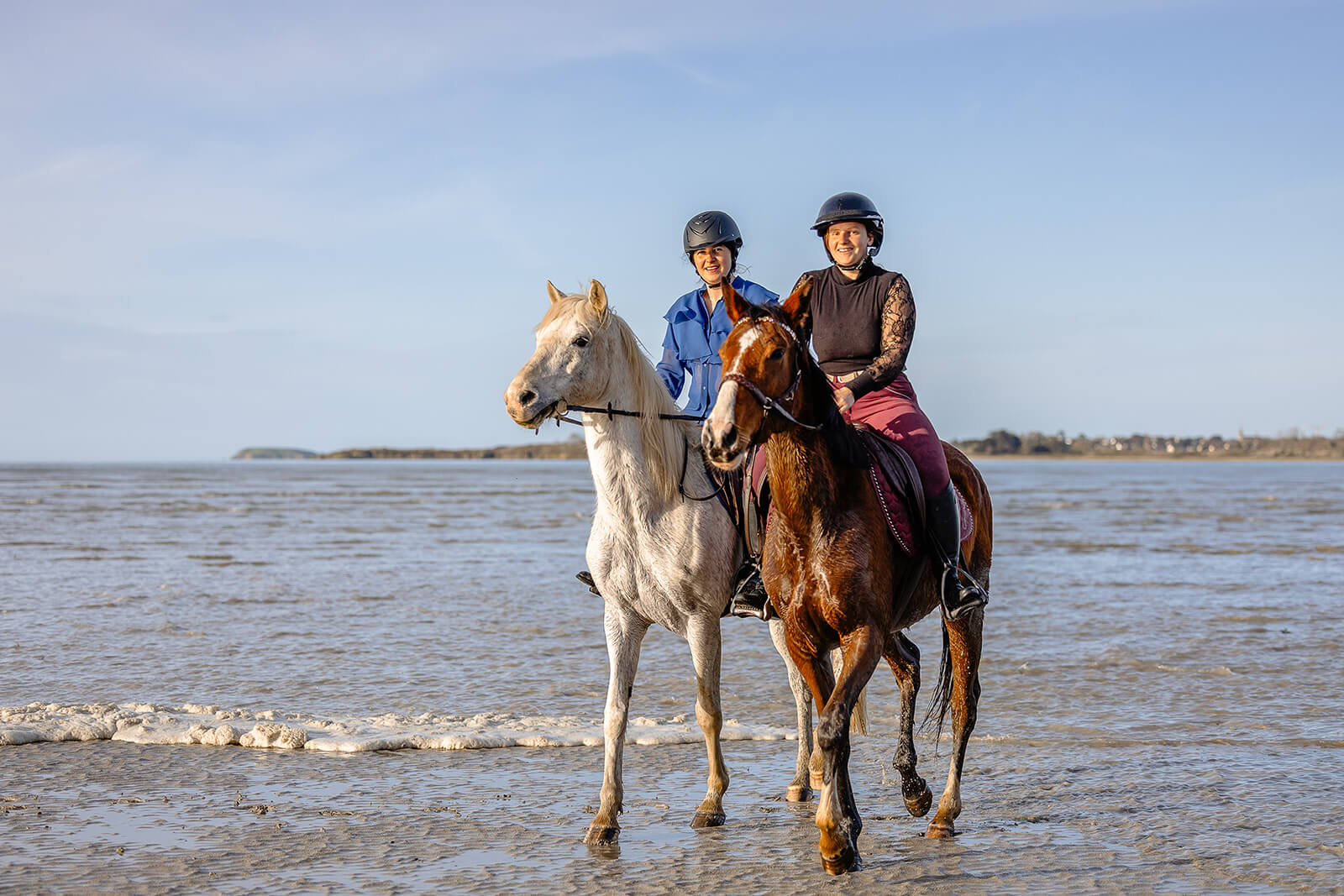 Deux cavalières galopant côte à côte sur la plage de la Côte d’Émeraude lors d’une séance photo équitation