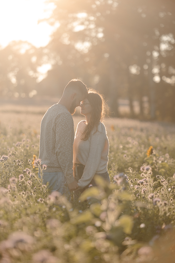 Couple se tenant la main dans un champ de fleurs à Liffré au crépuscule, photographie naturelle et poétique