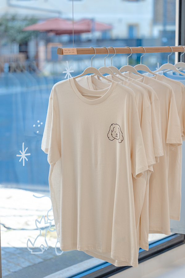 T-shirts crème illustrés du logo chien de la boutique Clebs suspendus en vitrine à Rennes, concept store dédié aux chiens
