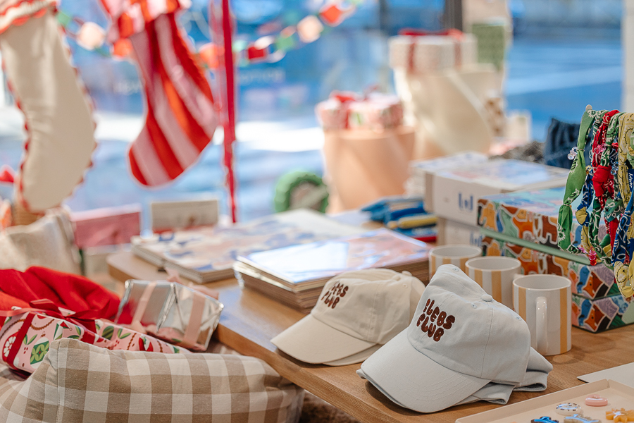 Casquettes “Clebs Club”, mugs, illustrations et accessoires colorés exposés sur une table en vitrine dans la boutique Clebs à Rennes, concept store dédié aux chiens<br />
