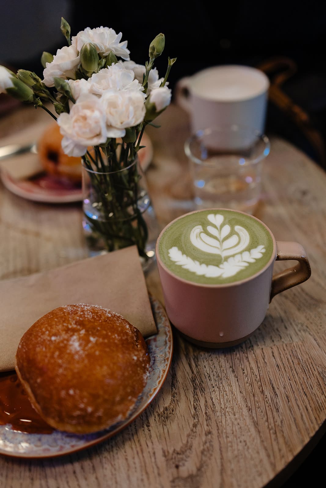 Un matcha latte crémeux et un beignet vegan gourmand servis sur une table en bois dans un café chaleureux d'Édimbourg.